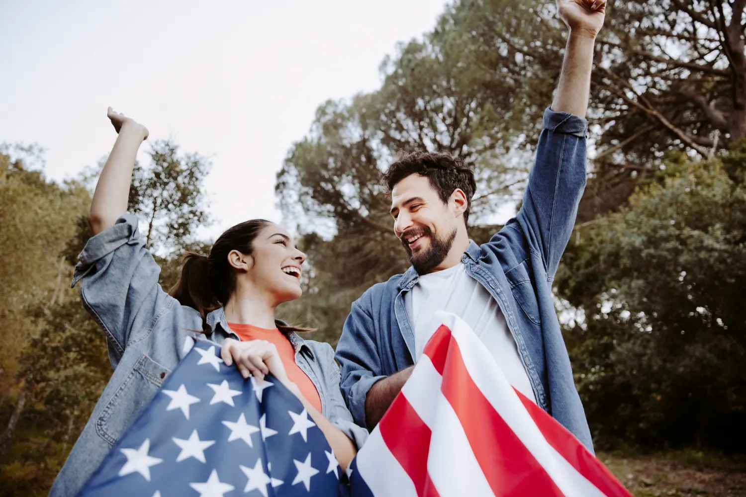 duas pessoas segurando a bandeira dos EUA, comemorando a conquista de dupla cidadania americana