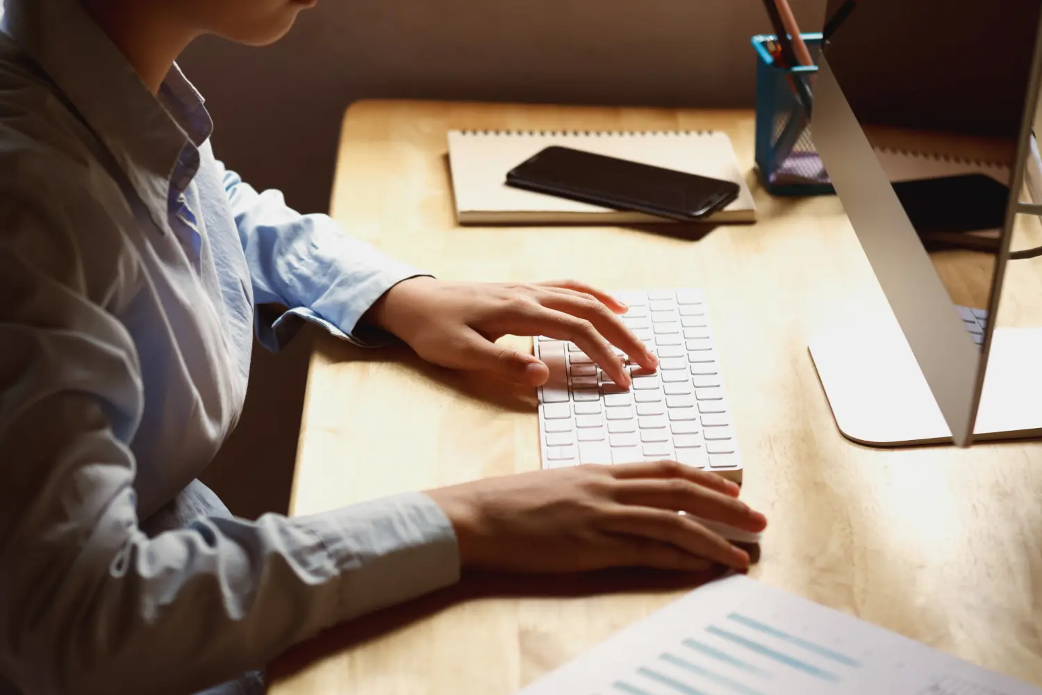 Pessoa com papéis e computador realizando a tradução de manuais técnicos.
