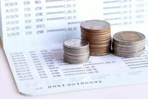 Extrato bancário sobre uma mesa com moedas por cima, representando tradução juramentada de extrato bancário.